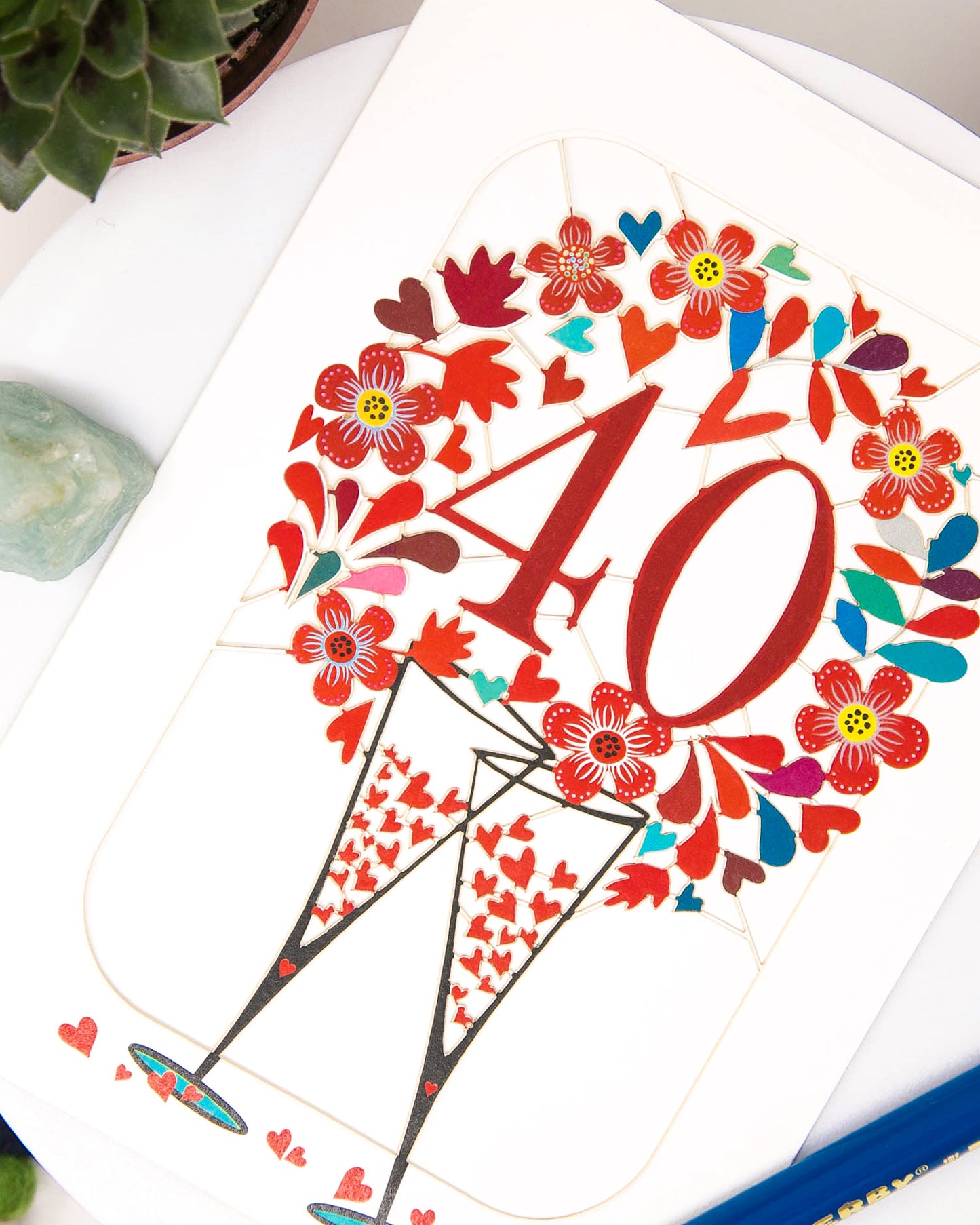 flatlay shot of the 40th Wedding Anniversary Card - Ruby Wedding Anniversary Card that features clanking champagne glasses surrounded with hearts | Dreamy London